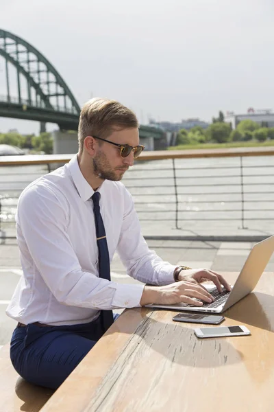 Knappe zakenman die op laptop buiten werkt — Stockfoto