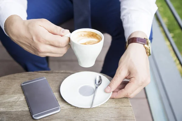 Zakenman handen met kopje koffie en telefoon — Stockfoto