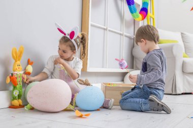 Paskalya yumurtaları ve bir tavşan bebek ile oynayan çocuklar