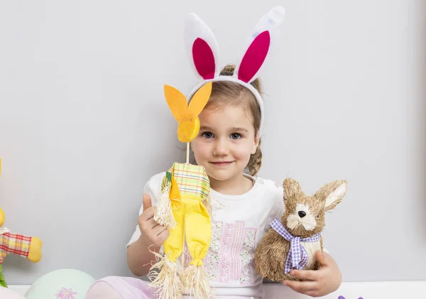 Chica jugando con los huevos de Pascua y una muñeca de conejo — Foto de Stock