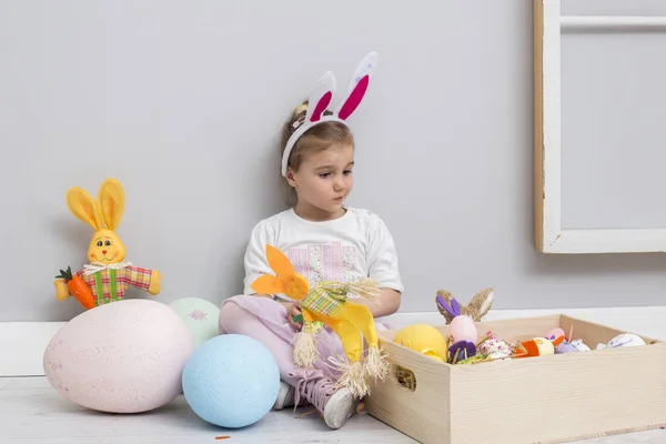 Chica jugando con los huevos de Pascua y una muñeca de conejo — Foto de Stock