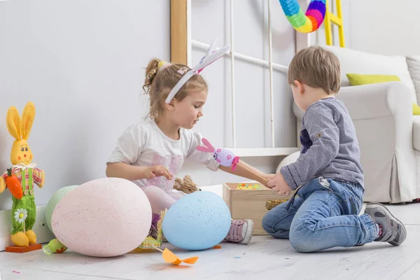 Niños jugando con huevos de Pascua y una muñeca de conejo — Foto de Stock