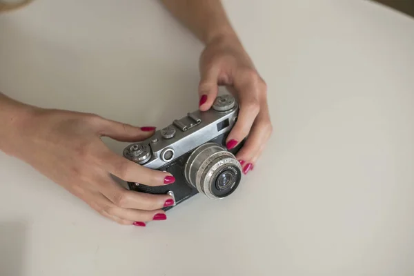 Женщина держит ретро-камеру на столе — стоковое фото