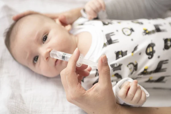 La mamma pulisce il naso del bambino con una siringa e un fisiologico — Foto Stock
