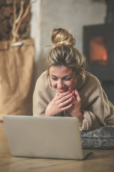 거실에서 여자는 바닥에 앉아서 친구와 컴퓨터 벽난로 감기에 담요로 — 스톡 사진