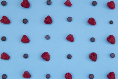 Mavi arka plan üzerinde renkli meyve desen taze yaban mersini ve ahududu Üstten Görünüm