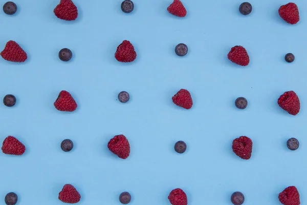 Top view of colorful fruit pattern of fresh blueberries and raspberries on blue background
