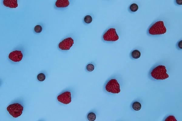 Top view of colorful fruit pattern of fresh blueberries and raspberries on blue background