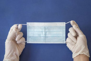 Elindeki koruyucu eldivende cerrahi maske var. Koronavirüs nedeniyle koruma