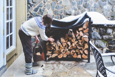 Vail, Colorado / ABD - 24 Aralık 2016: Vail, Colorado 'daki evinde yakacak odun toplayan genç bir kadın.