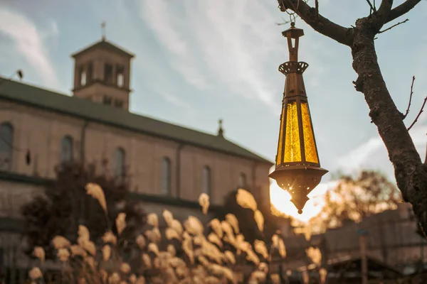 Indianapolis, Indiana / ABD - 22 Kasım 2019: Arka planda Aziz Joan of Arc Kilisesi 'nin yer aldığı altın saat içinde bir lamba aydınlatıldı.