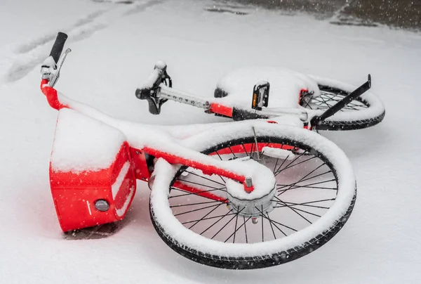 Kar fırtınası sırasında terk edilmiş bir motosiklet kaldırımda yatıyor.