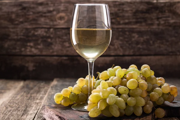 Bílé víno a hrozny. Víno a hrozny na retro dřevěný stůl — Stock fotografie
