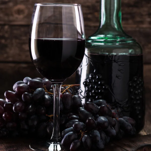 Glass of red wine, served with grapes on a wooden background — Stock Photo, Image