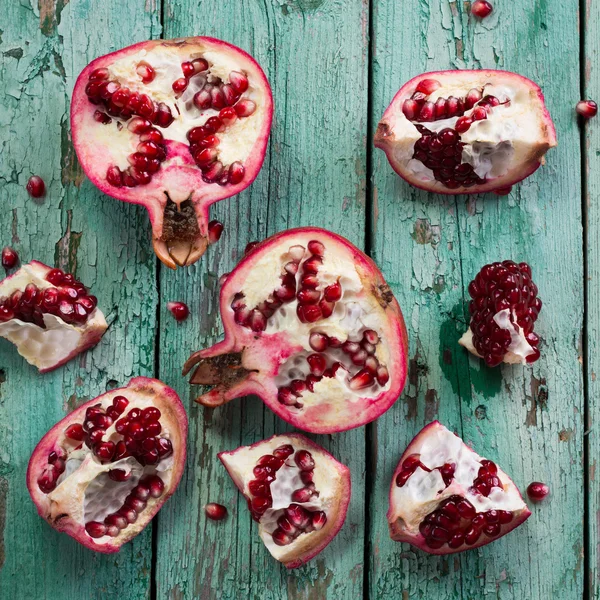 Fresh pomegranates in an old box with leaves. On wooden background. — Stock Photo, Image