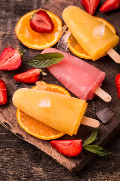 Ghiaccioli rinfrescanti alla frutta su tavolo di legno con bacche e frutta — Foto Stock