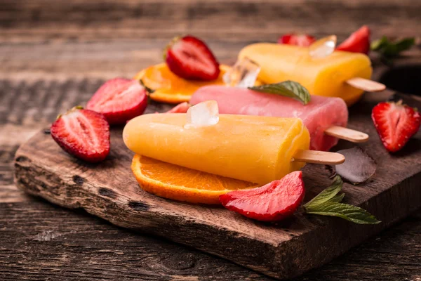 Ghiaccioli rinfrescanti alla frutta su tavolo di legno con bacche e frutta — Foto Stock