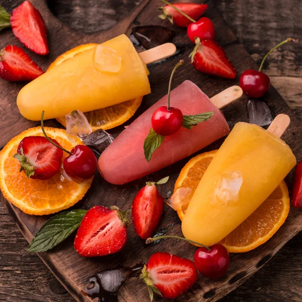 Ghiaccioli rinfrescanti alla frutta su tavolo di legno con bacche e frutta — Foto Stock