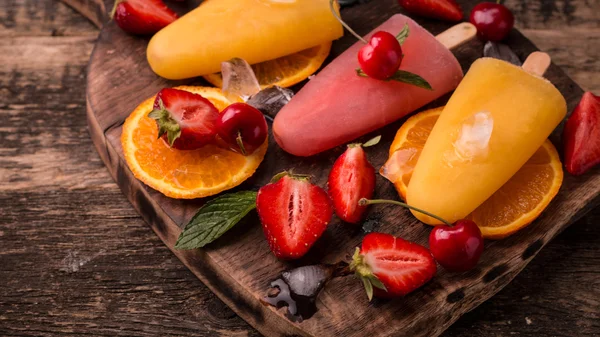 Ghiaccioli rinfrescanti alla frutta su tavolo di legno con bacche e frutta — Foto Stock