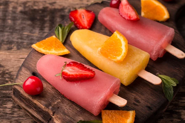 Ghiaccioli rinfrescanti alla frutta su tavolo di legno con bacche e frutta — Foto Stock