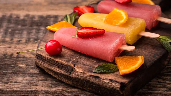 Ghiaccioli rinfrescanti alla frutta su tavolo di legno con bacche e frutta — Foto Stock