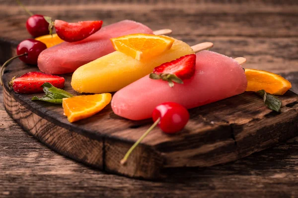 Ghiaccioli rinfrescanti alla frutta su tavolo di legno con bacche e frutta — Foto Stock