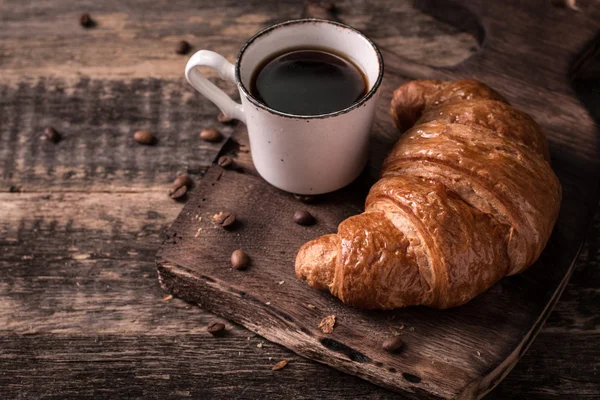 Frukost med kaffe och croissanter på vintage träbord — Stockfoto