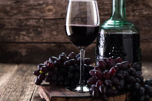 Glass of red wine, served with grapes on a wooden background Royalty Free Stock Photos