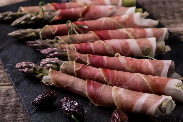 Parma jambonu bir kesme tahtası üzerinde sarılı taze organik kuşkonmaz — Stok fotoğraf