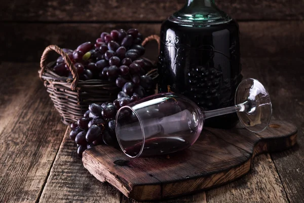 Bicchiere di vino rosso, servito con uva su fondo ligneo — Foto Stock