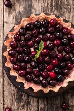 Ahşap antika masa üzerinde kiraz ve çırpılmış kremalı tart