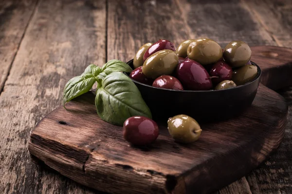 Oliven auf dunklem Holztisch mit Basilikum — Stockfoto