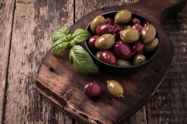 Olivy na dřevěný tmavý stůl s bazalkou — Stock fotografie