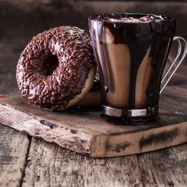 Donuts und eine Tasse Kaffee mit Schokolade auf einem Holztisch — Stockfoto