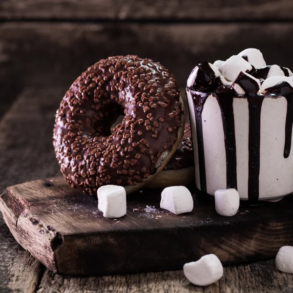 Пончики и чашку кофе с шоколадом на деревянном столе — стоковое фото