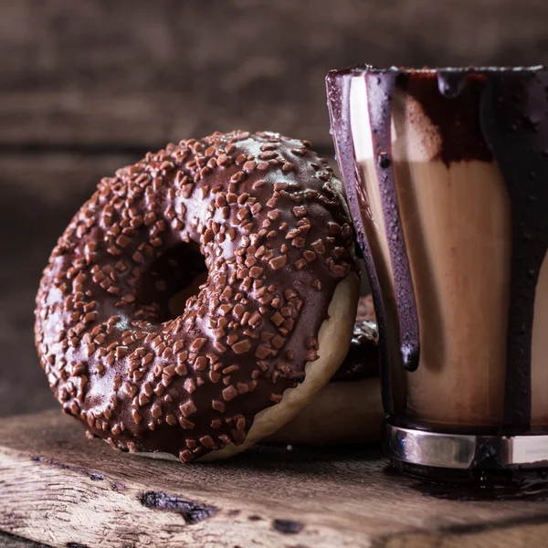 Donuts e uma xícara de café com chocolate em uma mesa de madeira — Fotografia de Stock