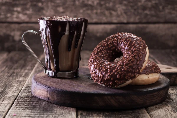 Пончики и чашку кофе с шоколадом на деревянном столе — стоковое фото
