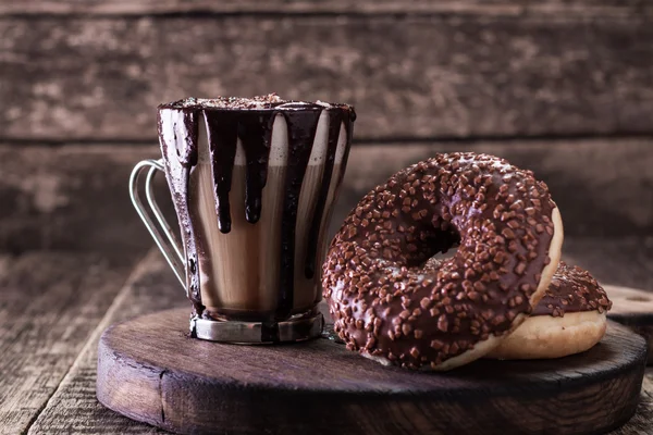 Fánk és egy csésze kávé, csokoládé, egy fából készült asztal — Stock Fotó