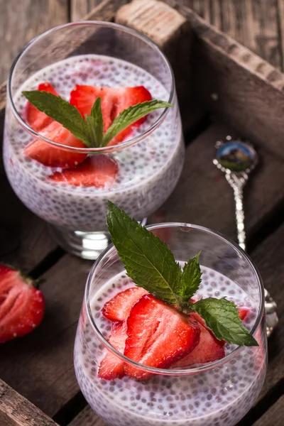 chia seed pudding with strawberries and min on wooden vintage background