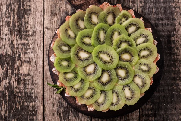 Kivi ve ahşap antika masa üzerinde krem şanti ile tart