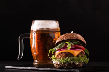 Ahşap bir masa üzerinde bir bira ile taze ve lezzetli hamburger.