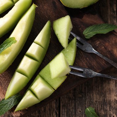 Dilimlenmiş taze kavun ve ahşap masa, sağlıklı gıda nane