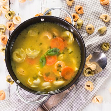 Beyaz ahşap masa üzerinde Tortellini lezzetli sebze çorbası