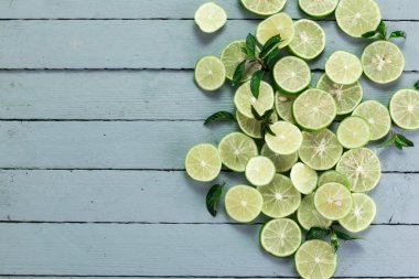 Arka plan kireç. Taze limon dilimleri ve nane yaprakları etrafında.