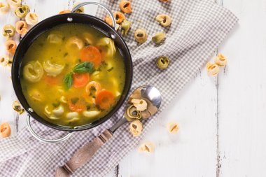 Beyaz ahşap masa üzerinde Tortellini lezzetli sebze çorbası