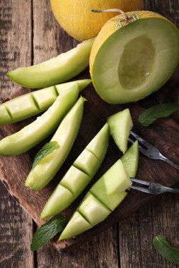 Dilimlenmiş taze kavun ve ahşap masa, sağlıklı gıda nane