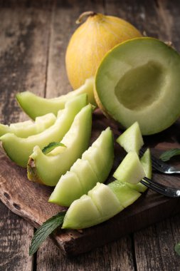 Dilimlenmiş taze kavun ve ahşap masa, sağlıklı gıda nane