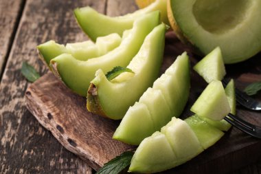 Dilimlenmiş taze kavun ve ahşap masa, sağlıklı gıda nane