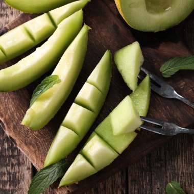 Dilimlenmiş taze kavun ve ahşap masa, sağlıklı gıda nane