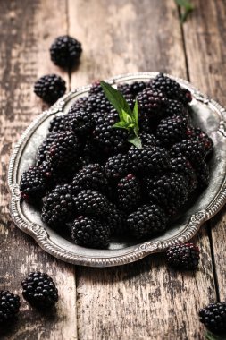 Ahşap arka plan üzerinde çuval bezi kumaş üzerine seramik bir kasede olgun böğürtlen kapatın. Rustik tarzı, seçici odak